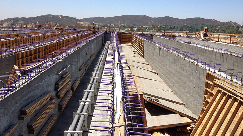 Construction site with many formed walls with rebar protruding.