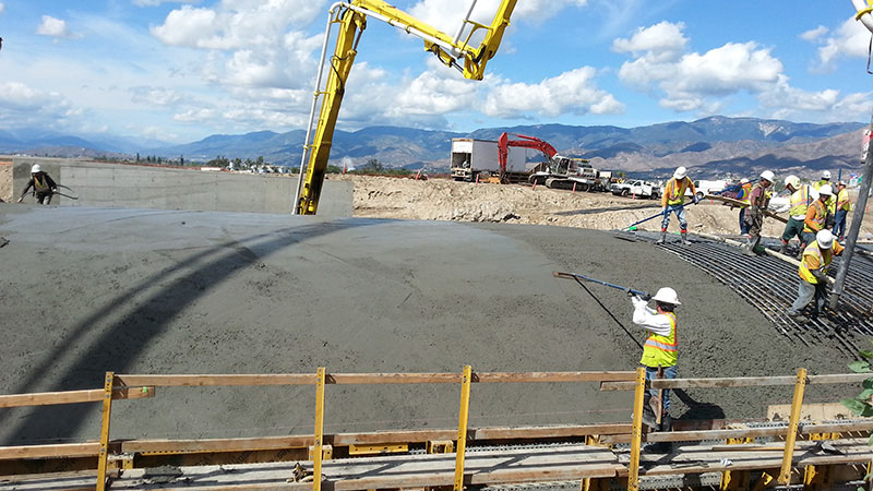 Concrete workers finishing a large section of a concrete berm.