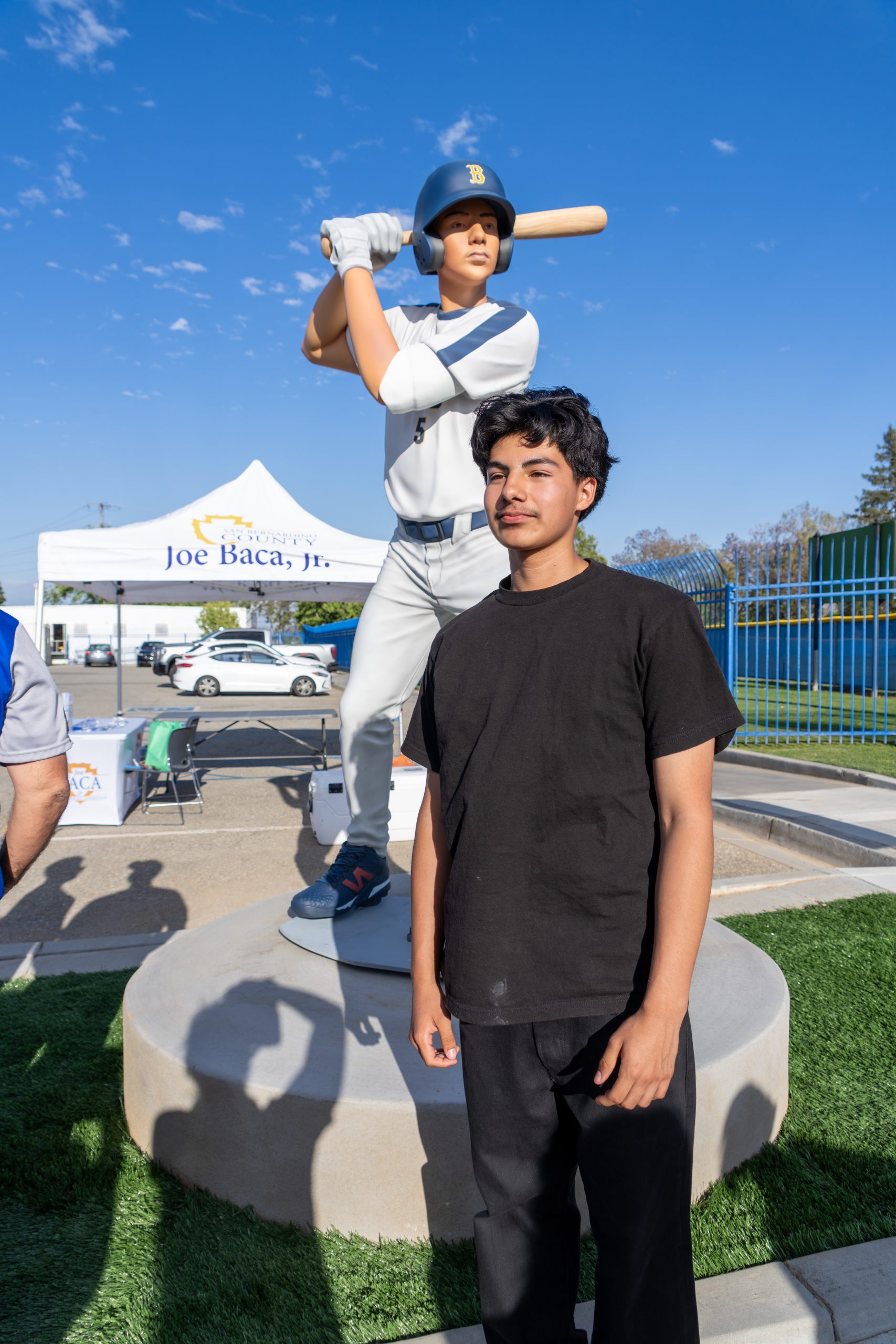 boy in black shirt looking off with statue of him behind.